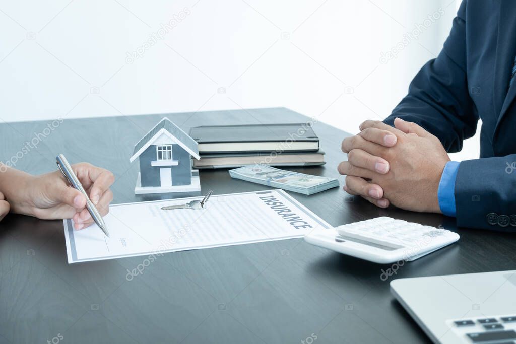 A real estate agent with a home model is talking to clients about renting a house and buying home insurance and contracting the contract after the formal negotiation is completed.