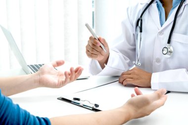 Kadın doktor hastanın geçmişinin incelenmesine oturdu ve semptomları netleştirmek için hastayı dinlemeye hazırdı. Tedavi ve sağlık kavramı.