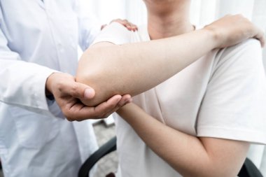 Erkek fizyoterapistler, rehabilitasyon merkezlerindeki hastaları muayene etmek için erkek hastalara dirsek yaralanmaları konusunda yardımcı oluyorlar. Rehabilitasyon fizyoterapi konsepti.