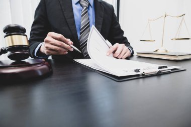 Profesyonel erkek avukatlar bir hukuk bürosunda çalışır. Teraziler, adalet terazileri, yargıç tokmağı ve dava belgeleri vardır. Hukuk ve adalet kavramları.
