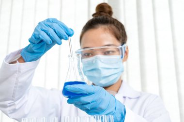 Tıp bilimcileri bir kimya laboratuvarında virüsü analiz etmek için deney şişesine yerleştirilmiş bir örnek bıraktılar. Bilimsel araştırma kavramları.