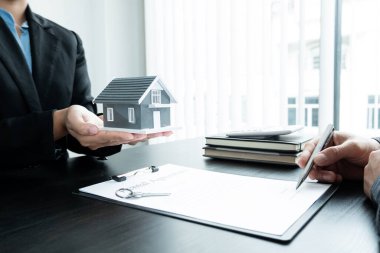 Emlakçı, kira sözleşmesini imzalayıp ev sigortasını resmen tamamladıktan sonra evi yeni sahibinin müşterisine verir. Kiralama ve sigorta kavramları.