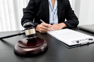 Profesyonel kadın avukatlar bir hukuk bürosunda çalışıyor. Teraziler, adalet terazileri, yargıç tokmağı ve dava belgeleri var. Hukuk ve adalet kavramları.