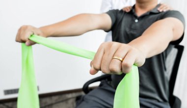 Kadın fizyoterapistler, tedavi merkezinde kol yaralanması, kol çekme ve kas gevşemesi olan erkek hastalara yardım ediyorlar. Fizyoterapi kavramları.