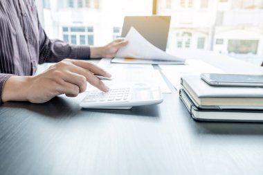 Bir erkek işadamının elleri, ofisteki bakiyeleri özetlemek amacıyla mali bir grafikte yıllık gelir ve giderleri analiz ediyor ve hesaplıyor..