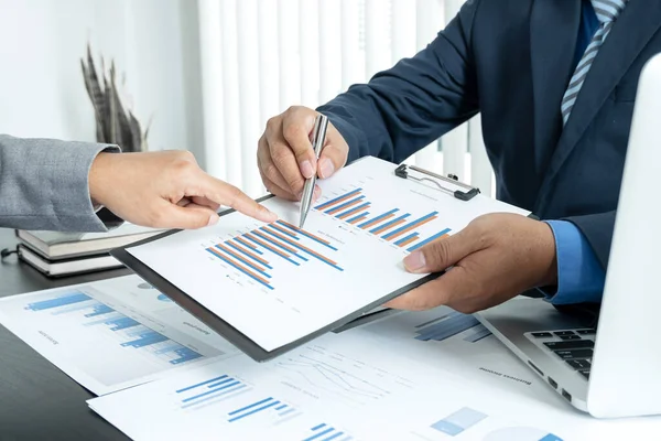 İki iş lideri çizelgeler, finansal grafikler hakkında konuşuyor. Sonuçları gösteren planlama stratejilerini analiz ediyor ve hesaplıyor. Ticari başarı oluşturma süreçlerini de..