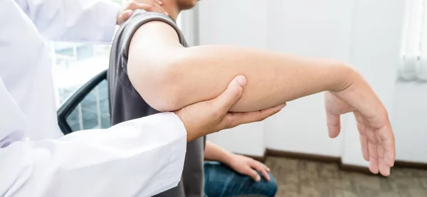 Kadın fizyoterapistler, rehabilitasyon merkezlerindeki hastaları muayene etmek için erkek hastalara dirsek yaralanmaları konusunda yardımcı oluyorlar. Rehabilitasyon fizyoterapi konsepti.