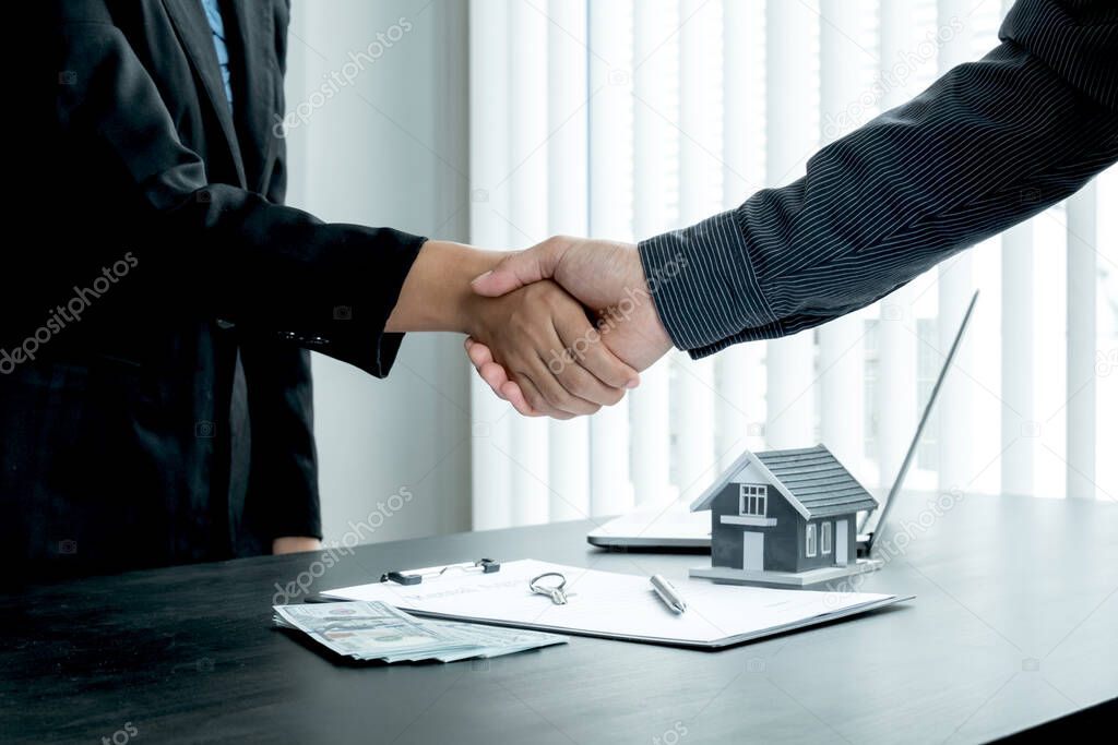 A real estate agent and clients shake hands after completing the home insurance contract negotiation and signing a formal contract. Rental and home insurance concepts.