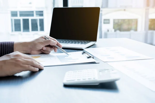 The hands of a male businessman are analyzing and calculating the annual income and expenses in a financial graph that shows results To summarize balances overall in office.