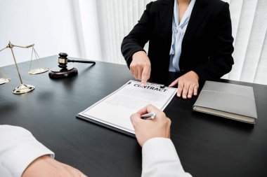 Bir kadın avukat ya da yargıç müvekkillerine adalet ve kovuşturma konusunda danışmanlık yapıyor. Teraziler, yargıç tokmağı, yasal belgeler, hukuk hizmetleri kavramı..