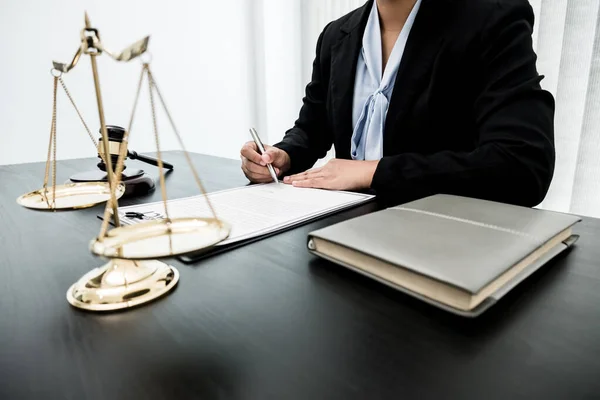 Profesyonel kadın avukatlar bir hukuk bürosunda çalışıyor. Teraziler, adalet terazileri, yargıç tokmağı ve dava belgeleri var. Hukuk ve adalet kavramları.