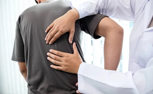 男性患者は診察と治療のために腰痛を持つ理学療法士に相談した リハビリテーション理学療法の概念 — ストック写真