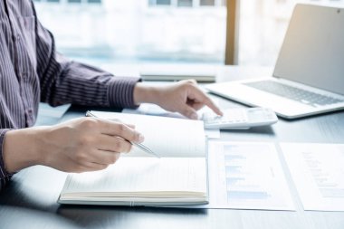 Bir erkek işadamının elleri, ofisteki bakiyeleri özetlemek amacıyla mali bir grafikte yıllık gelir ve giderleri analiz ediyor ve hesaplıyor..