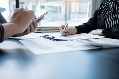 Sonuçları gösteren çizelge ve grafikleri tartışan iki iş lideri ofiste büyük bir başarı için yeni bir strateji başlatmayı planlıyorlar..