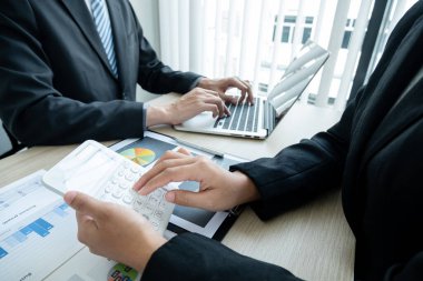 İki iş lideri çizelgeler, finansal grafikler hakkında konuşuyor. Sonuçları gösteren planlama stratejilerini analiz ediyor ve hesaplıyor. Ticari başarı oluşturma süreçlerini de..