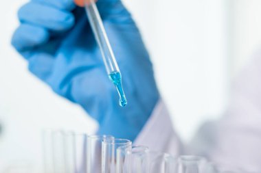 Tıp bilimcileri bir kimya laboratuvarında virüsü analiz etmek için test tüpüne bir örnek pipet yerleştirdiler. Bilimsel araştırma kavramları.