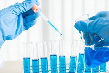 Tıp bilimcileri bir kimya laboratuvarında virüsü analiz etmek için test tüpüne bir örnek pipet yerleştirdiler. Bilimsel araştırma kavramları.