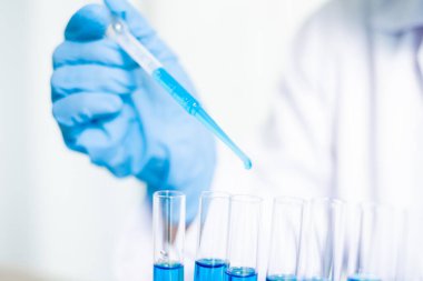 Tıp bilimcileri bir kimya laboratuvarında virüsü analiz etmek için test tüpüne bir örnek pipet yerleştirdiler. Bilimsel araştırma kavramları.