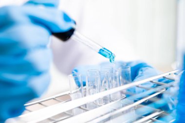 Tıp bilimcileri bir kimya laboratuvarında virüsü analiz etmek için test tüpüne bir örnek pipet yerleştirdiler. Bilimsel araştırma kavramları.