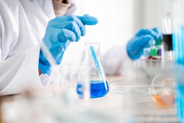 Tıp bilimcileri bir kimya laboratuvarında virüsü analiz etmek için deney şişesine yerleştirilmiş bir örnek bıraktılar. Bilimsel araştırma kavramları.