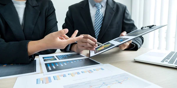 İki iş lideri çizelgeler, finansal grafikler hakkında konuşuyor. Sonuçları gösteren planlama stratejilerini analiz ediyor ve hesaplıyor. Ticari başarı oluşturma süreçlerini de..