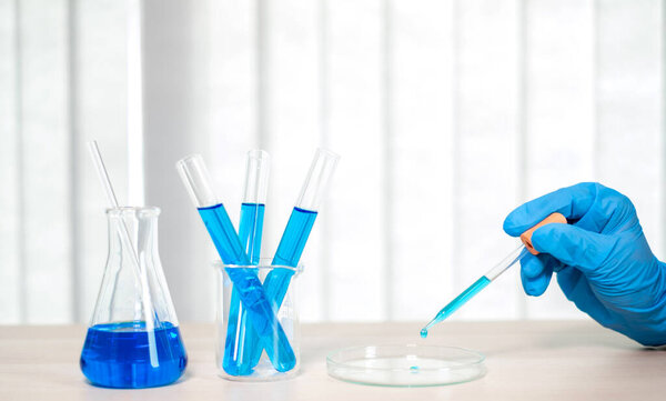 Medical scientists released a sample pipetted into test glassware to analyze the virus in a chemical laboratory. Scientific research concepts.