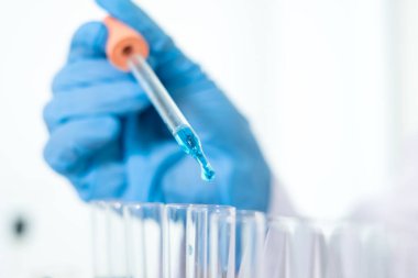 Tıp bilimcileri bir kimya laboratuvarında virüsü analiz etmek için test tüpüne bir örnek pipet yerleştirdiler. Bilimsel araştırma kavramları.