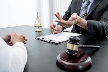 Bir erkek avukat ya da bir yargıç müvekkillerine yargı adaleti ve kovuşturma hakkında ölçekli danışmanlık yapıyor..