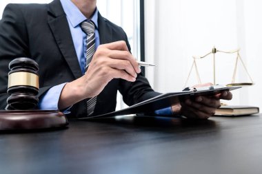 Profesyonel erkek avukatlar bir hukuk bürosunda çalışır. Teraziler, adalet terazileri, yargıç tokmağı ve dava belgeleri vardır. Hukuk ve adalet kavramları.