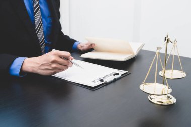 Bir hukuk firmasında çalışan profesyonel bir erkek avukatın terazisi, adalet terazisi, adalet ile ilgili belgeleri ve davaları vardır. Hukuk ve adalet kavramları.