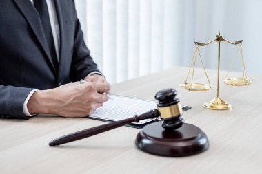 Yargıç tokmağı, profesyonel erkek avukatlar bir hukuk bürosunda çalışıyor. Teraziler, adalet terazileri, yargıç tokmağı ve dava belgeleri var. Hukuk ve adalet kavramları.