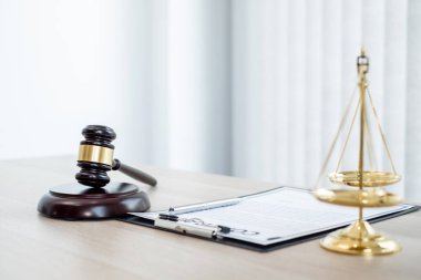 Yargıcın hukuk bürosundaki tokmağında teraziler, adalet terazileri ve dava belgeleri var. Hukuk ve adalet kavramları.