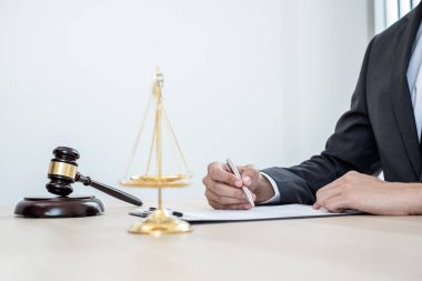 Profesyonel erkek avukatlar bir hukuk bürosunda çalışır. Teraziler, adalet terazileri, yargıç tokmağı ve dava belgeleri vardır. Hukuk ve adalet kavramları.