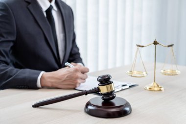 Yargıç tokmağı, profesyonel erkek avukatlar bir hukuk bürosunda çalışıyor. Teraziler, adalet terazileri, yargıç tokmağı ve dava belgeleri var. Hukuk ve adalet kavramları.