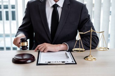 Yargıç tokmağı, profesyonel erkek avukatlar bir hukuk bürosunda çalışıyor. Teraziler, adalet terazileri, yargıç tokmağı ve dava belgeleri var. Hukuk ve adalet kavramları.