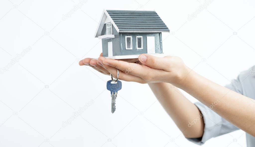 The hand of the real estate agent holding the house model and the keys Loan and home concept.