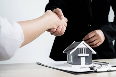 İş adamları ve emlakçılar ev sigortası ve sözleşme imzalama görüşmelerini tamamladıktan sonra el sıkışıyorlar. Ev sigortası kavramı.