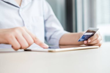 İş kadınının elinde bir kredi kartı var ve ofisteki online alışveriş ve internet ödemeleri için bir dizüstü bilgisayar kullanıyor..