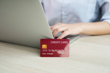 İş kadınının elinde bir kredi kartı var ve ofisteki online alışveriş ve internet ödemeleri için bir dizüstü bilgisayar kullanıyor..