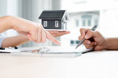 Kiralık evleri olan bir emlakçı ve müşteriler için ev kiralama sözleşmesi imzalayan bir emlakçı. Ev kiralama ve sigorta konsepti.