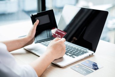 İş kadınının elinde bir kredi kartı var ve ofisteki online alışveriş ve internet ödemeleri için bir dizüstü bilgisayar kullanıyor..
