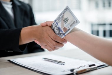 İş adamlarının fotoğrafı, el sıkışma ve dolar notu, şirketteki yolsuzluğa rüşvet vermek için bir sözleşme imzalama. Rüşvet ve yolsuzluk kavramı.