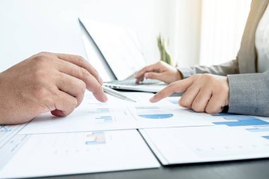 İki iş lideri çizelgeler, finansal grafikler hakkında konuşuyor. Sonuçları gösteren planlama stratejilerini analiz ediyor ve hesaplıyor. Ticari başarı oluşturma süreçlerini de..