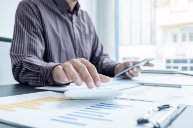 Bir erkek işadamının elleri, ofisteki bakiyeleri özetlemek amacıyla mali bir grafikte yıllık gelir ve giderleri analiz ediyor ve hesaplıyor..