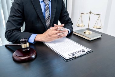 Profesyonel erkek avukatlar bir hukuk bürosunda çalışır. Teraziler, adalet, adalet çekici ve dava belgeleri vardır. Hukuk ve adalet kavramları.