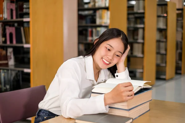 Young Asian women are searching for books and reading from the bookshelves in the college library to research and develop themselves in education.