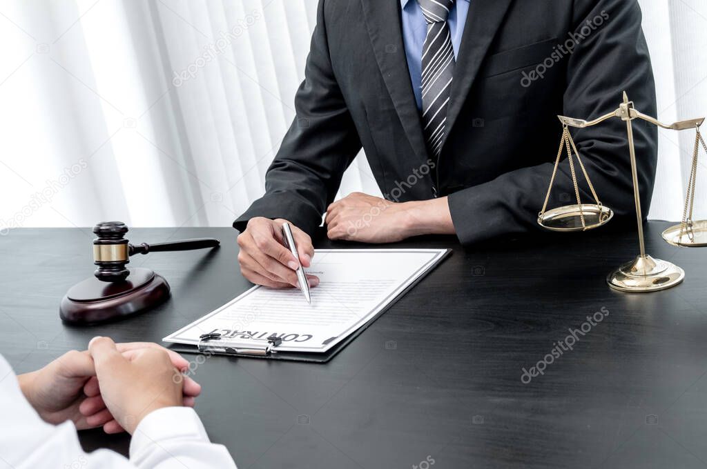 A male lawyer or a judge counseling clients about judicial justice and prosecution with scales, judges gavel, legal documents legal services concept.