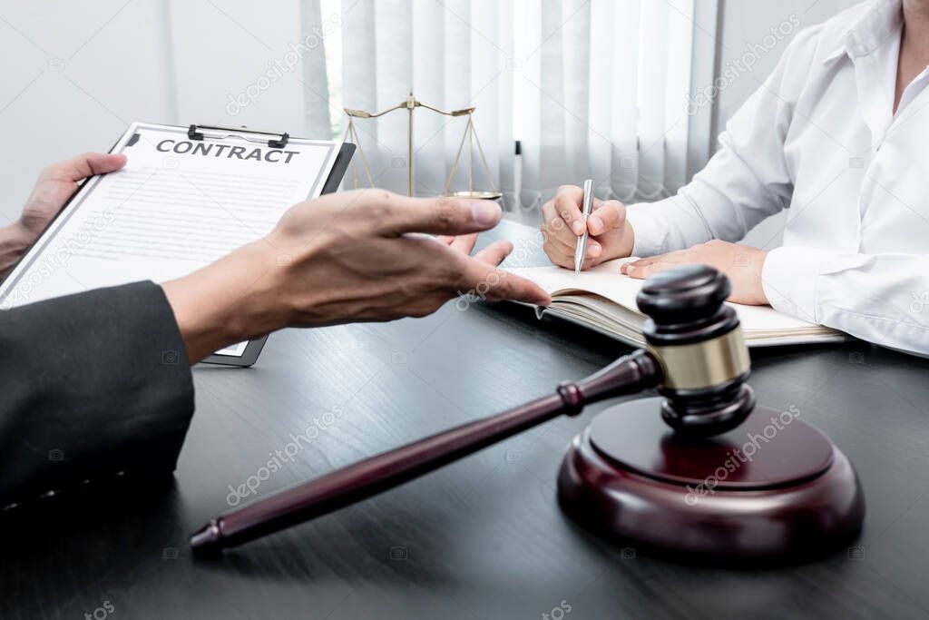 A male lawyer or a judge counseling clients about judicial justice and prosecution with scales, judges gavel, legal documents legal services concept.