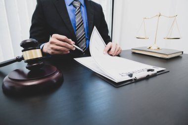 Profesyonel erkek avukatlar bir hukuk bürosunda çalışır. Teraziler, adalet terazileri, yargıç tokmağı ve dava belgeleri vardır. Hukuk ve adalet kavramları.