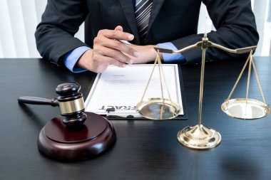 Profesyonel erkek avukatlar bir hukuk bürosunda çalışır. Teraziler, adalet terazileri, yargıç tokmağı ve dava belgeleri vardır. Hukuk ve adalet kavramları.